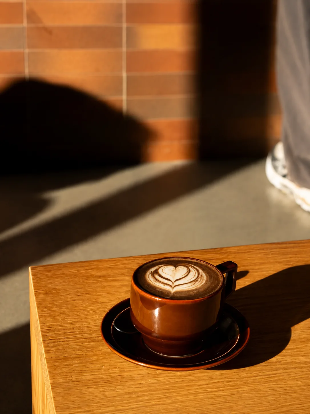 A flat white catching the morning light at Akin Cafe