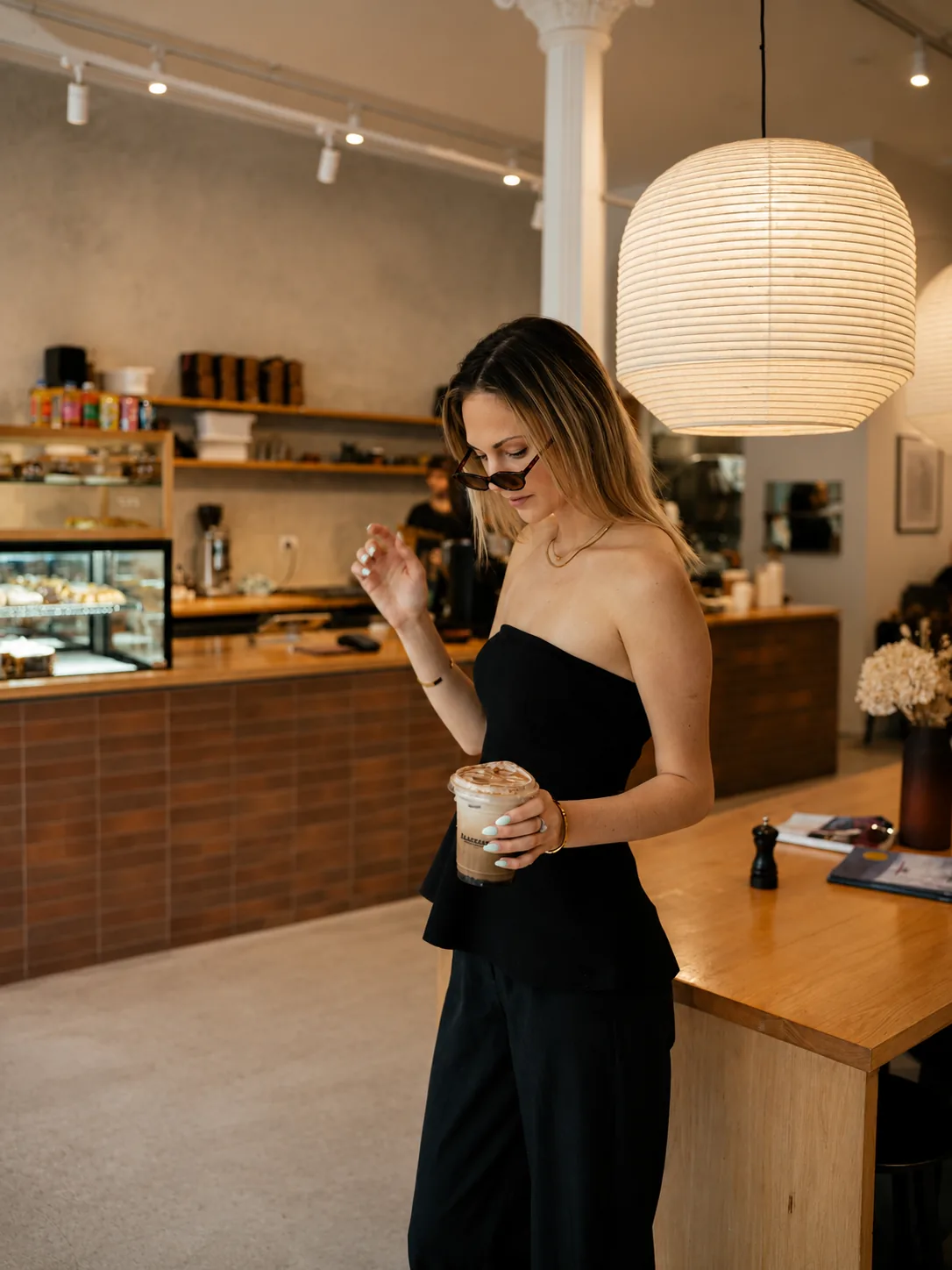 A guest holding an iced coffee inside Akin Cafe