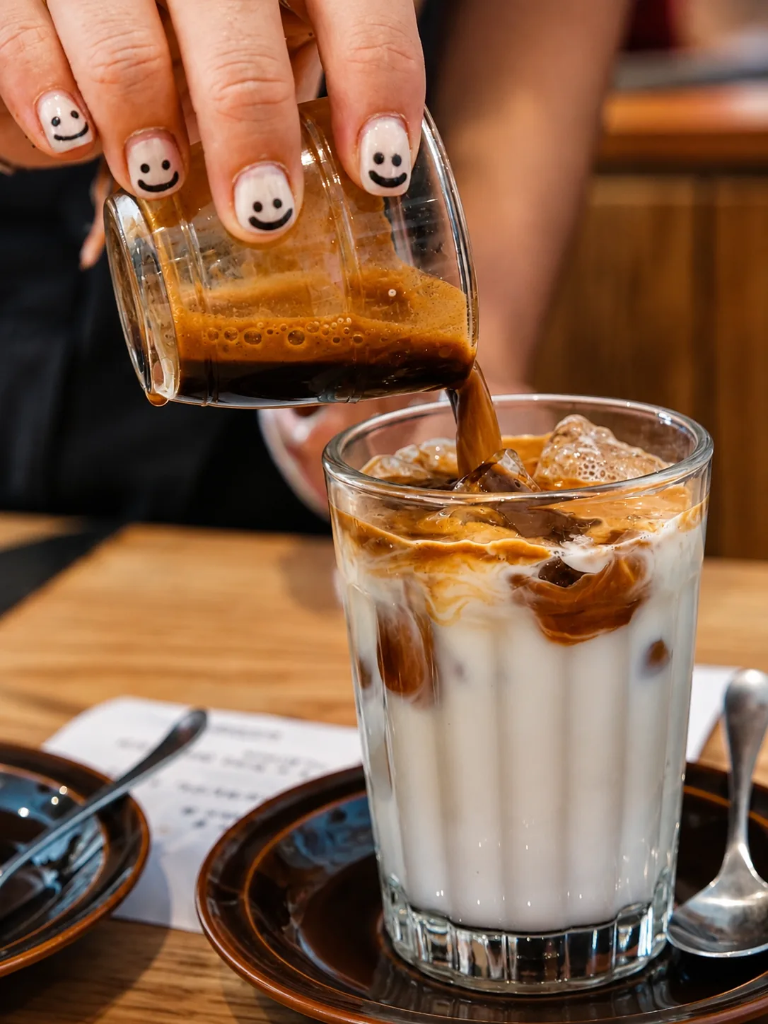 An iced milk coffee being poured at Akin Cafe