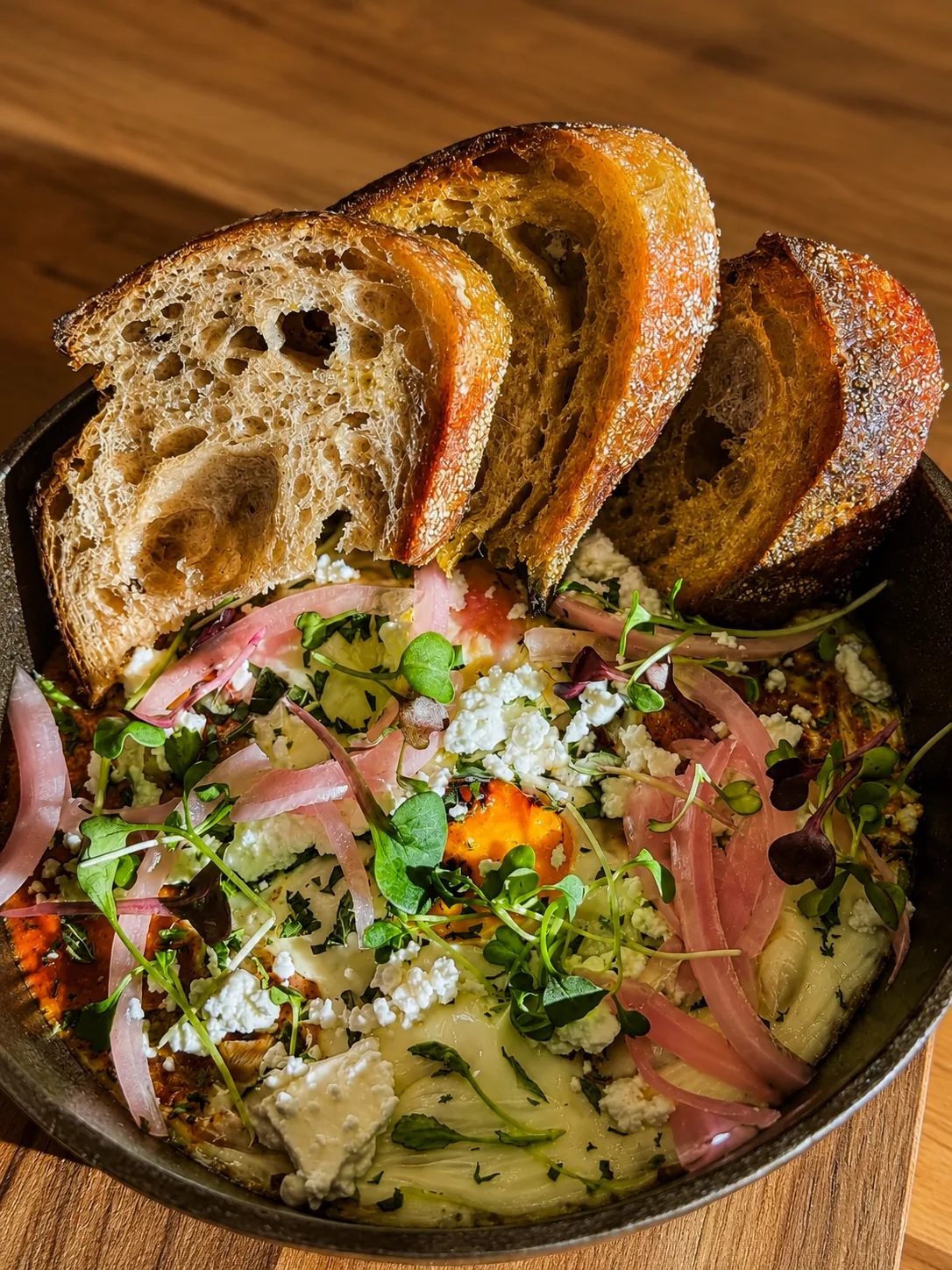 A savoury Akin Cafe breakfast plate with eggs, sourdough and pickled onion